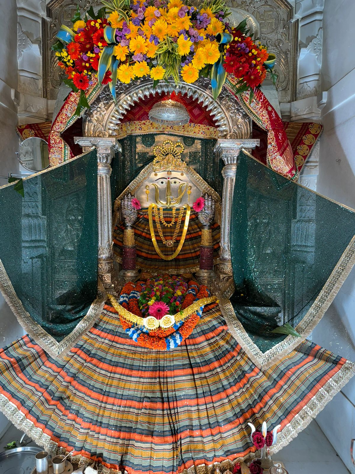 Rani Sati Dadi in multicolour pleated poshak with green veil and floral arch at Neemuch Dham.