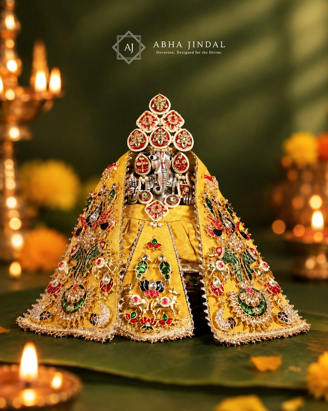 Ganesh Ji in a yellow draped Rajwada poshak with colourful ornamental panels, a long central panel and coordinated red crown details.