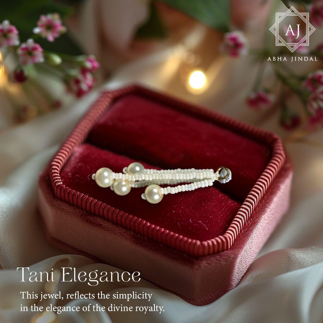 White bead strands ending in larger round beads in a red velvet box