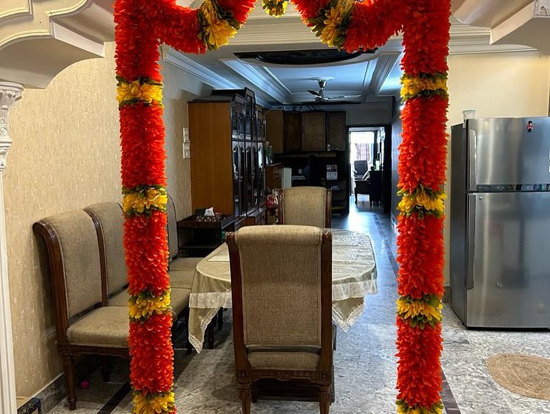 Doorway framed by long red flower garlands with yellow and green bands