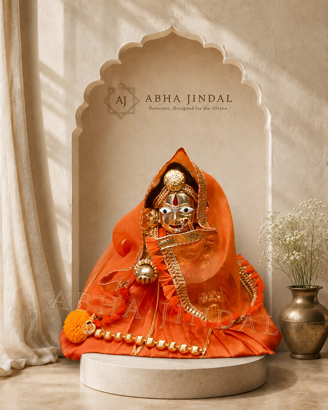 Front view of Laddu Gopal framed by a saffron-orange veil with floral and gold-tone accents