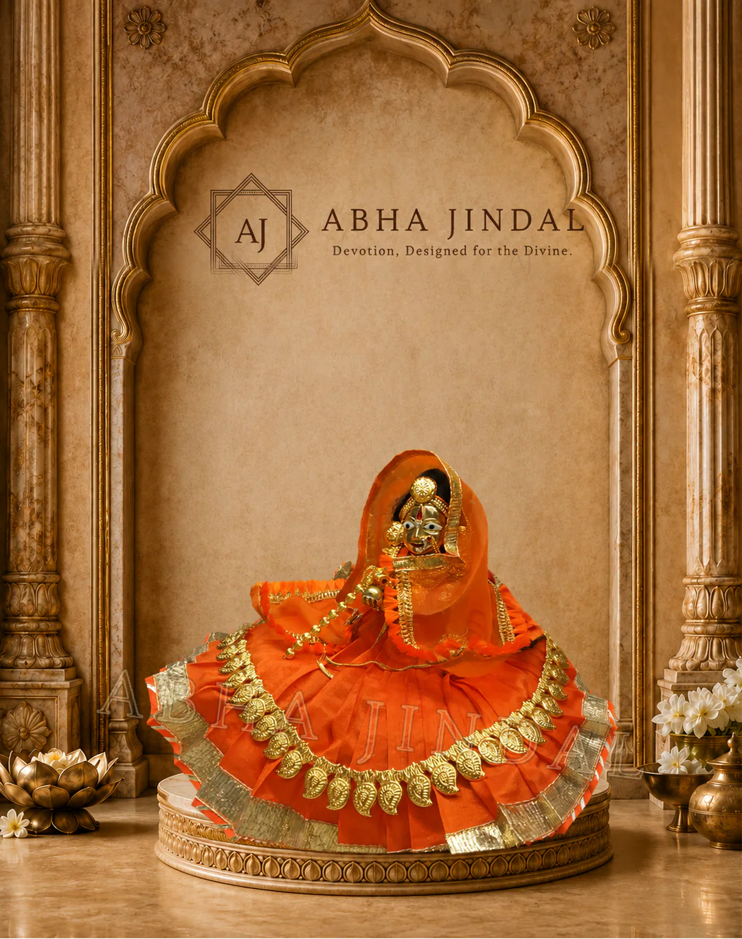 Laddu Gopal in saffron-orange pleats with red accents and a repeated coin-style gold-tone border