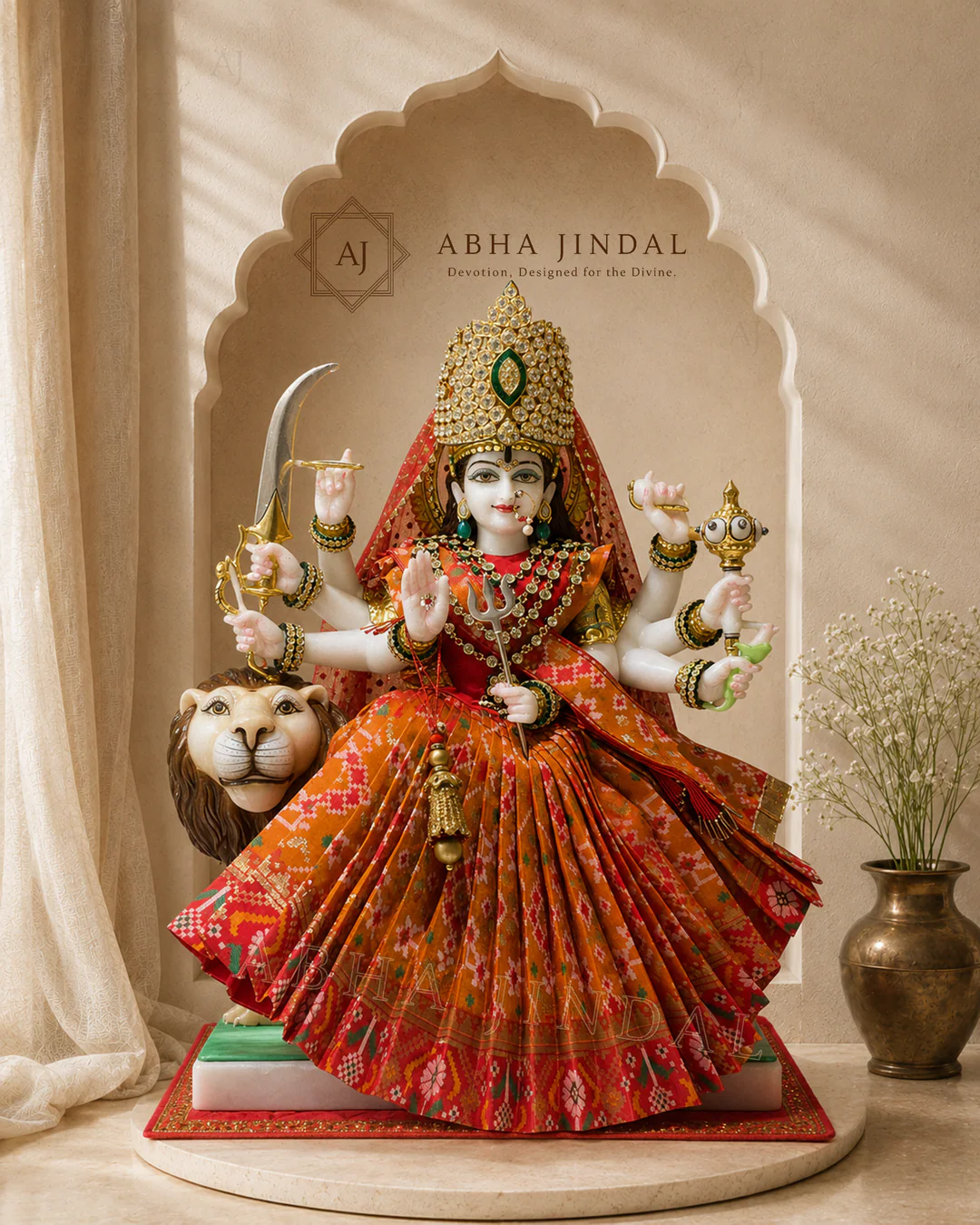 Mata Rani in orange and red attire with a lion figure, tall crown and broad pleated skirt