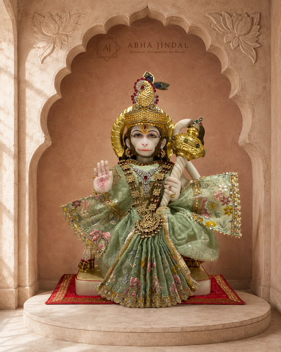 Standing Hanuman Ji in sage-green floral attire with a tall crown, layered necklaces and mace