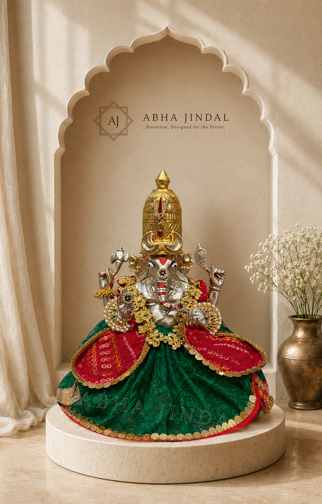 Seated Ganesh Ji in green and red attire with a broad circular skirt, layered necklaces and crown