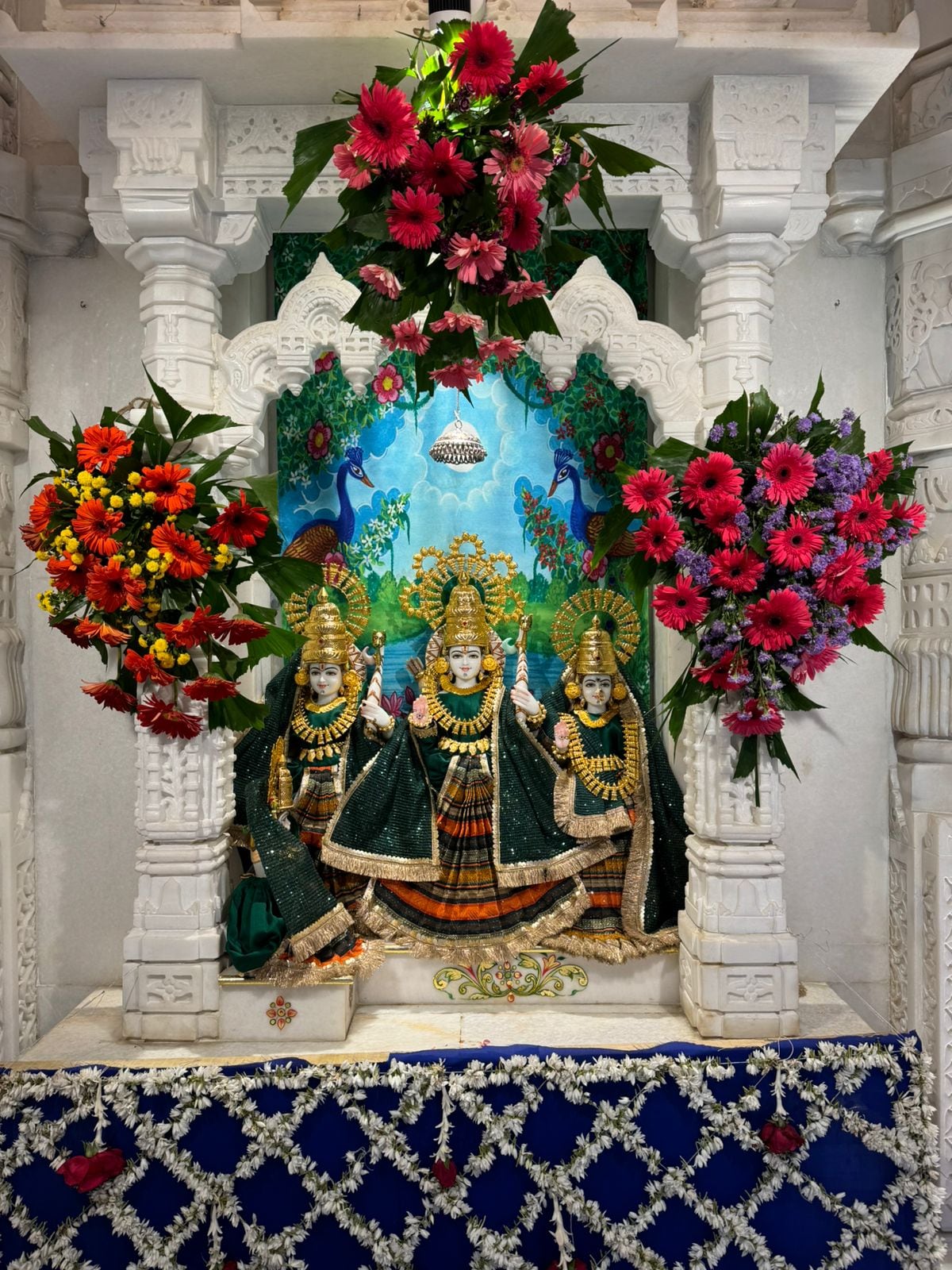 Three crowned shrine figures in matching black and orange attire at Dadi Dham, Neemuch.