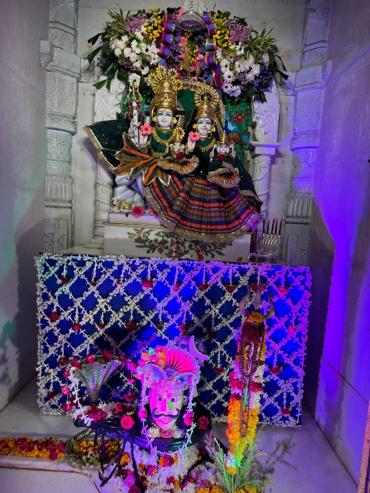 Grouped crowned shrine figures in coordinated attire under coloured temple lighting.