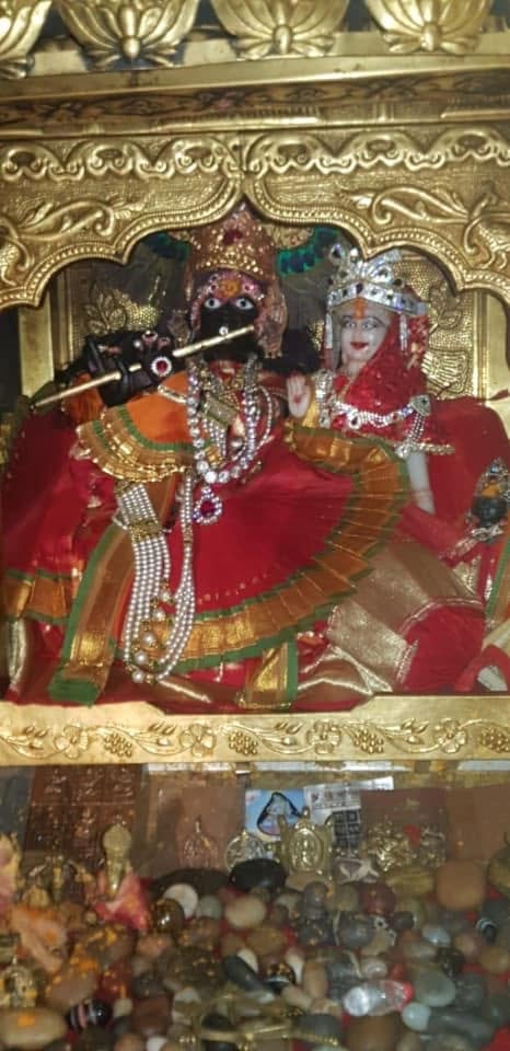 Paired subsidiary shrine figures in coordinated red and orange attire within a silver-toned enclosure at Shri Salasar Balaji Mandir.