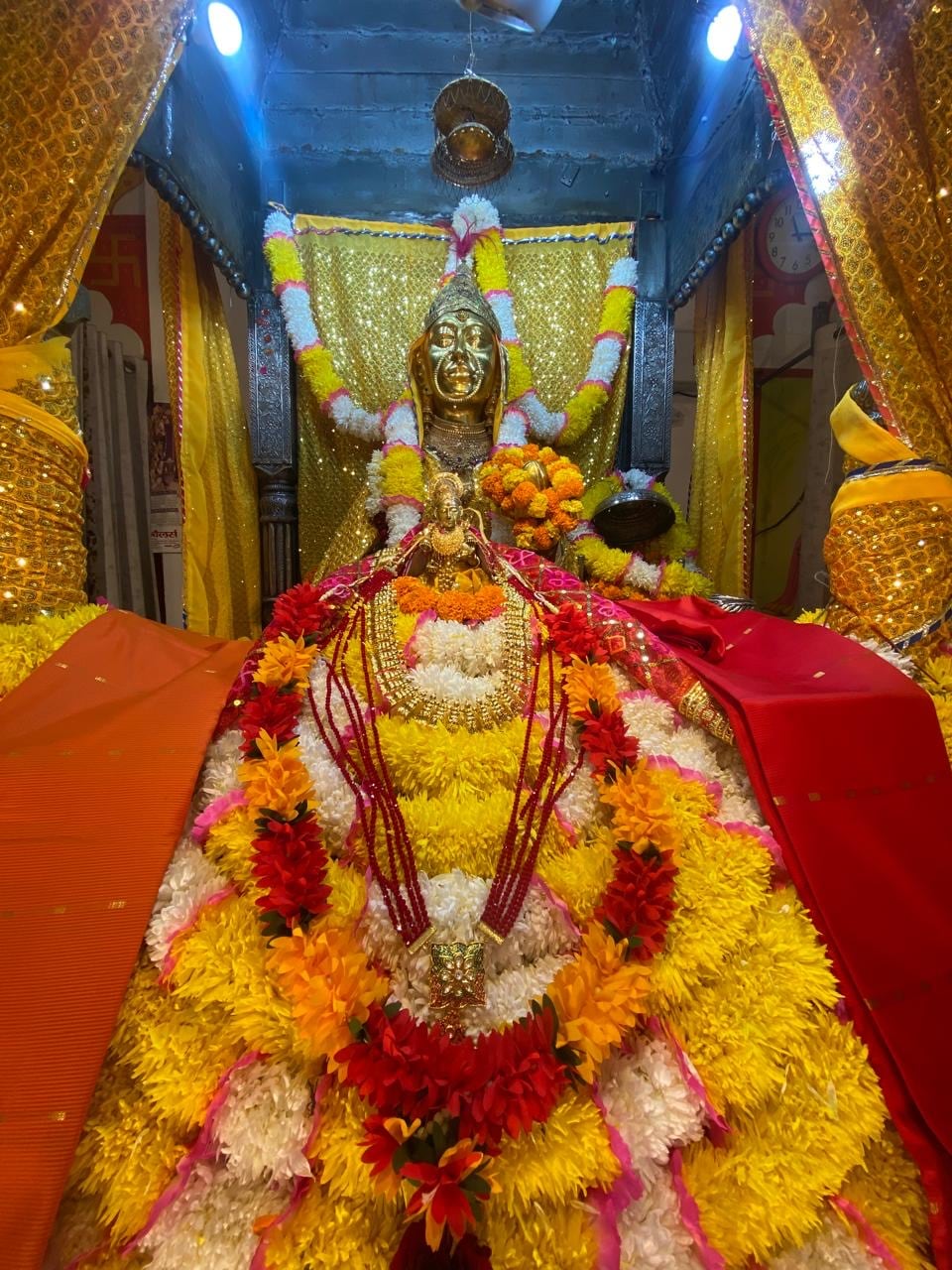 Sheetla Mata shrine in a yellow and red floral arrangement within a gold-toned sanctum in Gurugram.